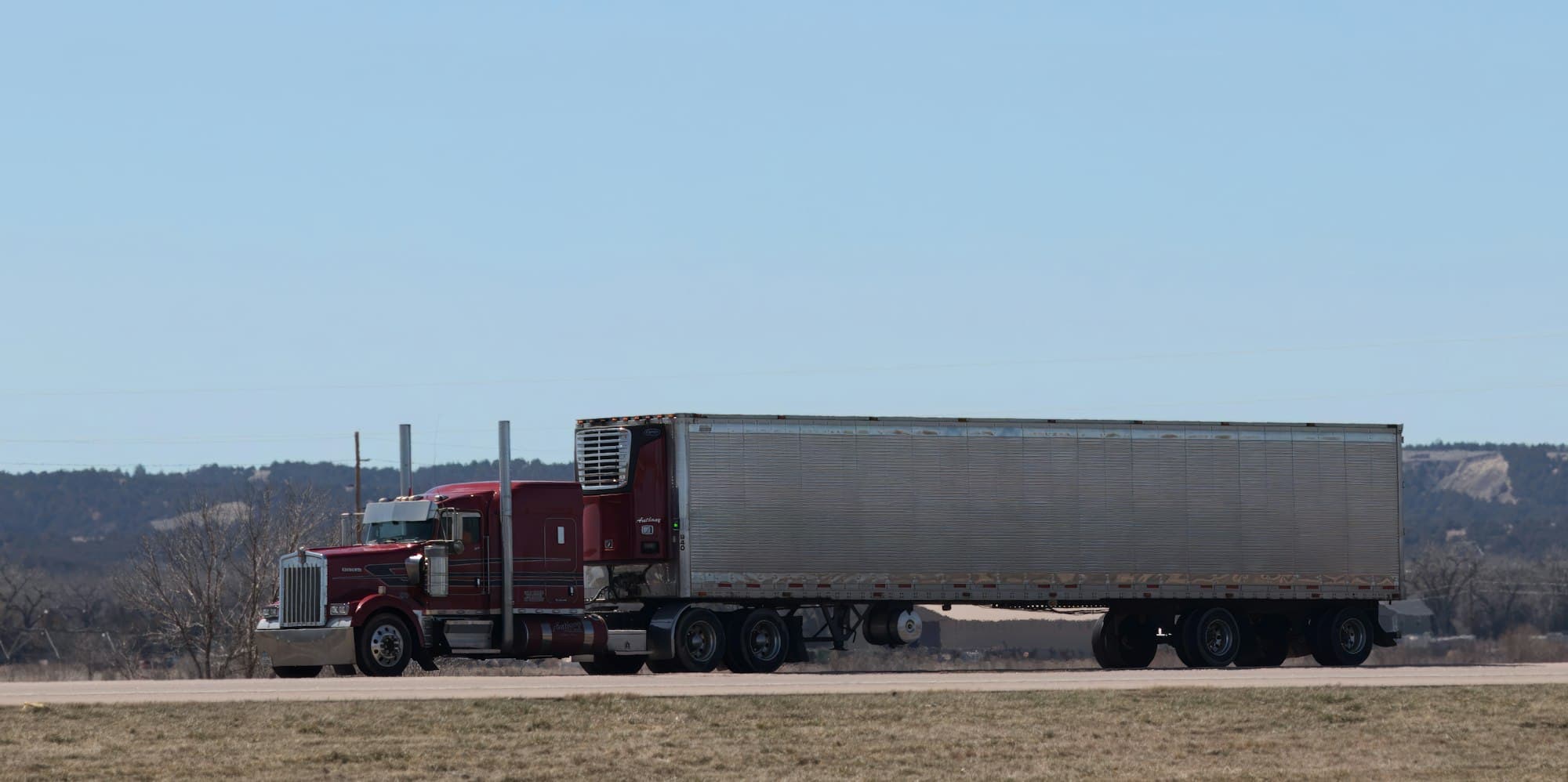 A Clelland truck with a refrigerated trailer travelling along an open highway